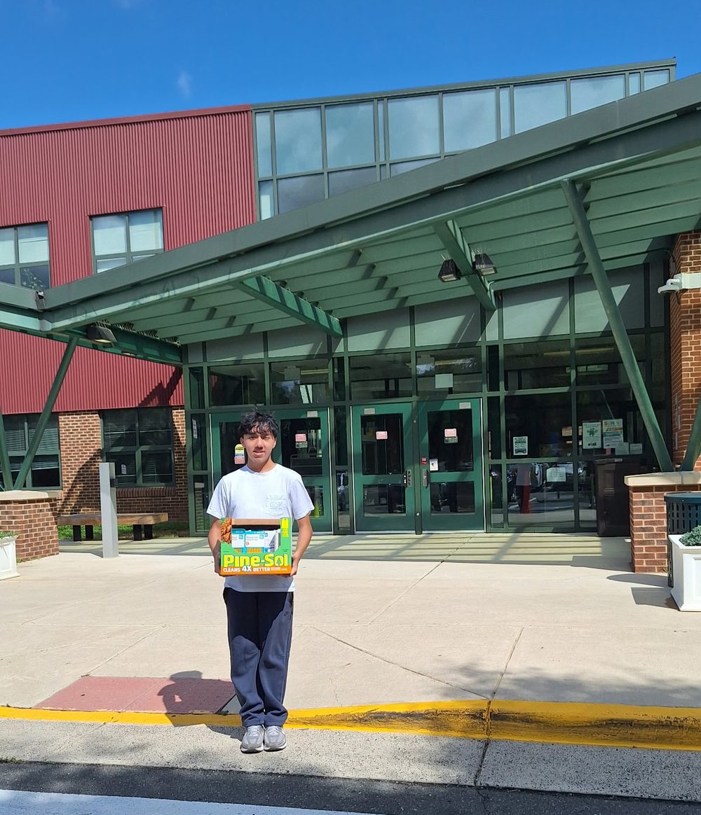 Cesar Carlos outside Graham Road Elementary School carrying a box of donated supplies.