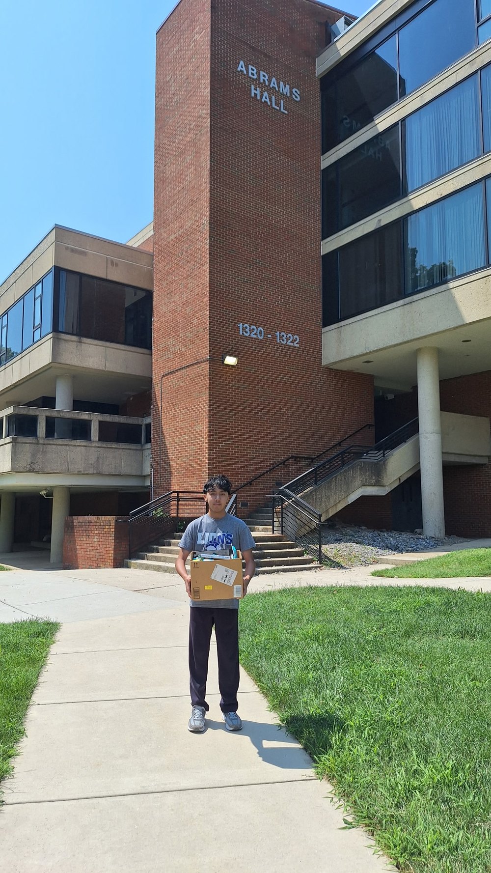 A Generation Supply team member carrying a box of donated school supplies outside Abrams Hall in Washington, DC.